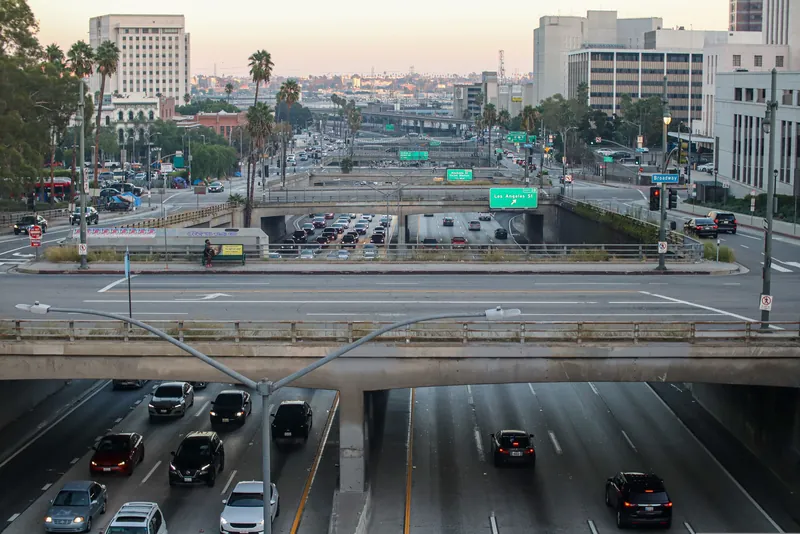 Captured during the day, showcasing the bustling highways and iconic buildings of Los Angeles.
