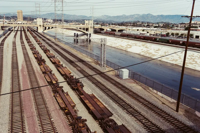 Aerial view of railway tracks and industrial bridge over a river in an urban setting.