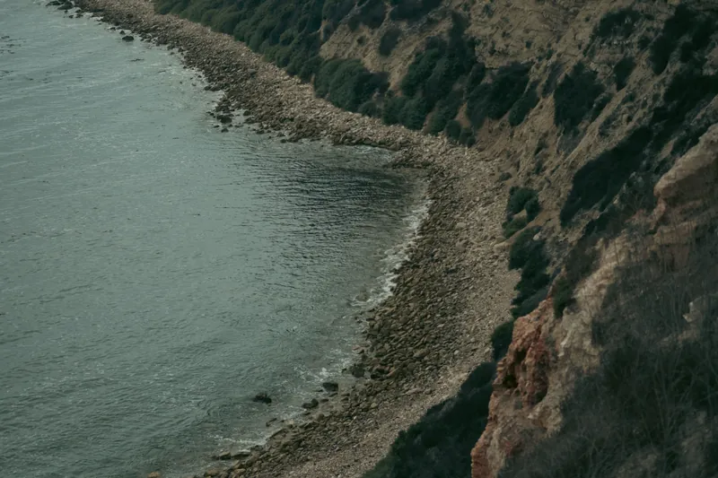 Aerial view of a rugged coastline with rocky shore and waves hitting the cliffs, capturing nature's raw beauty.