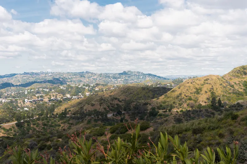 Breathtaking panorama of Los Angeles hills with skyline under a cloudy blue sky.