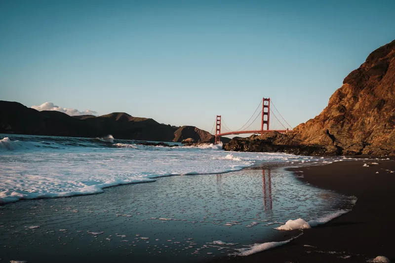 View of the Golden Gate Bridge from a scenic beach at sunset in San Francisco, California.