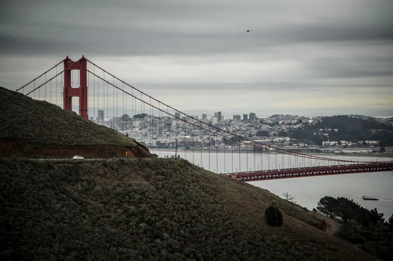 Golden Gate Bridge with San Francisco skyline, captured under overcast skies.