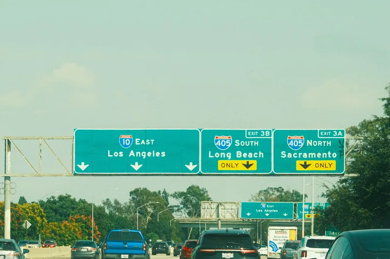 Highway signs with directions to Los Angeles, Long Beach, and Sacramento on a clear day.
