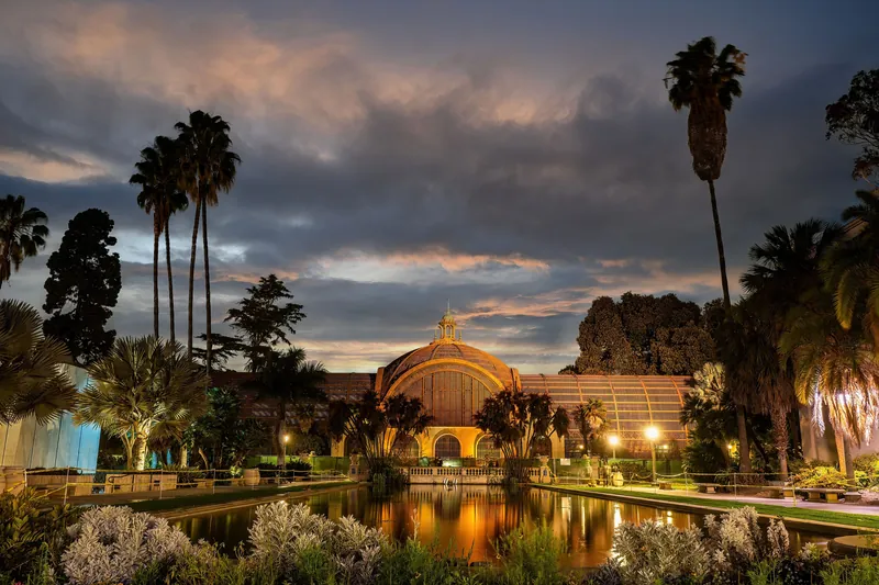 Dramatic sunset over the historic Botanical Building and reflecting pond in Balboa Park, San Diego.