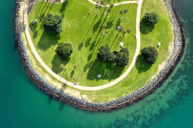 A stunning birds-eye view of a lush green park on a peninsula surrounded by blue water.