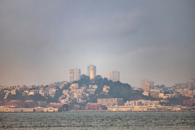 Beautiful view of San Francisco's skyline featuring Coit Tower at dusk with a calming sea foreground.