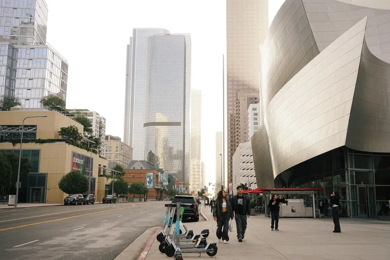 Downtown city street featuring modern skyscrapers and people on sidewalks, Los Angeles.