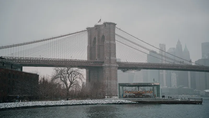 Capture of the Brooklyn Bridge with a fresh snowfall in New York City, showcasing a serene winter scene.