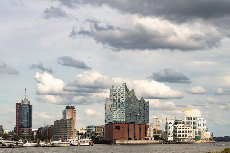 Scenic view of the Elbphilharmonie and Hamburg skyline along the waterfront with cloudy sky.
