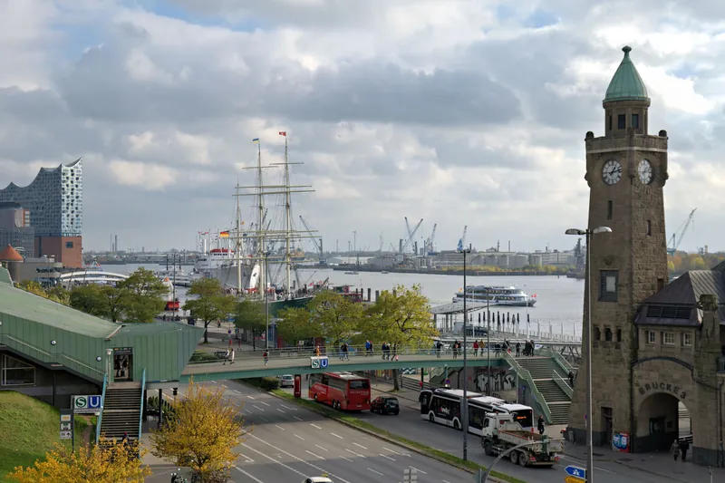 A busy day at Hamburg's harbor featuring the Elbphilharmonie, historic ships, and clock tower.
