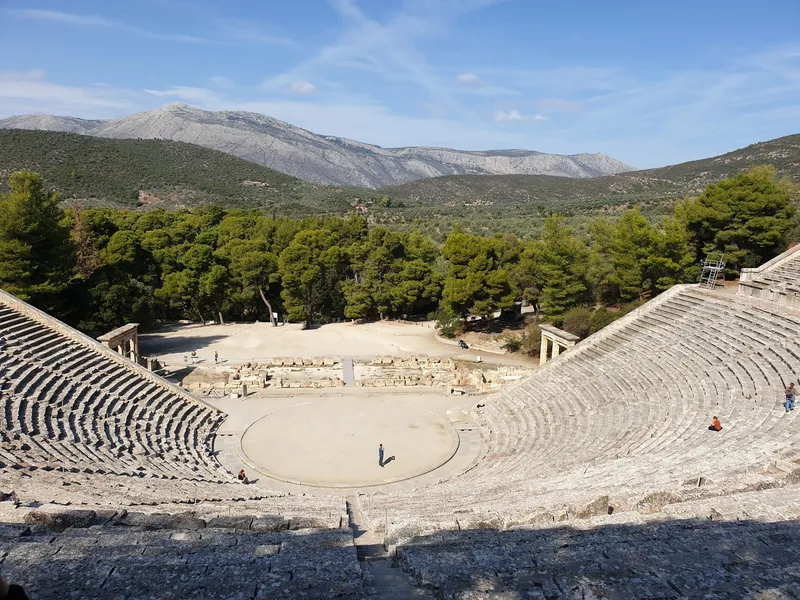 A scenic view of the ancient Epidaurus theater surrounded by lush nature.