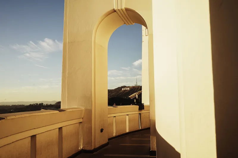 A glimpse of the iconic Hollywood sign through an archway at Griffith Observatory, Los Angeles.