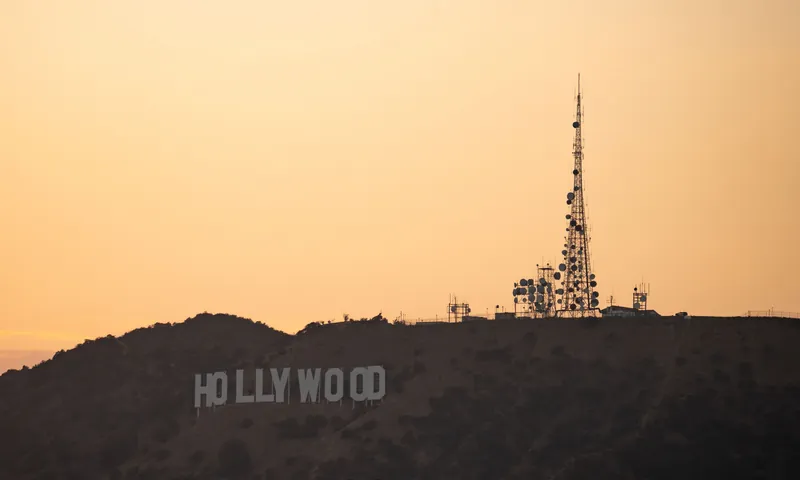 Silhouette of Hollywood Sign and communication tower against the golden hour sky in Los Angeles.