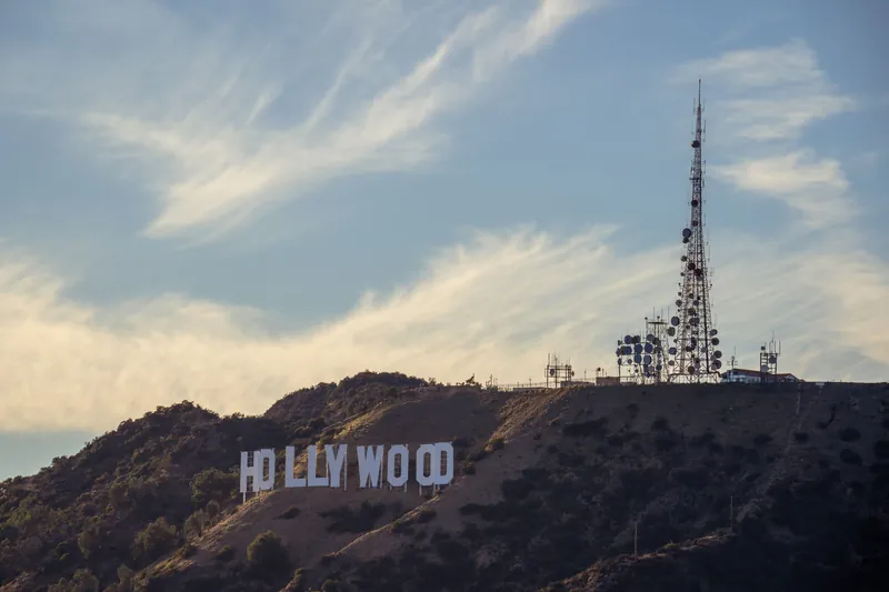View of the iconic Hollywood sign and cell tower on a sunny day in Los Angeles.
