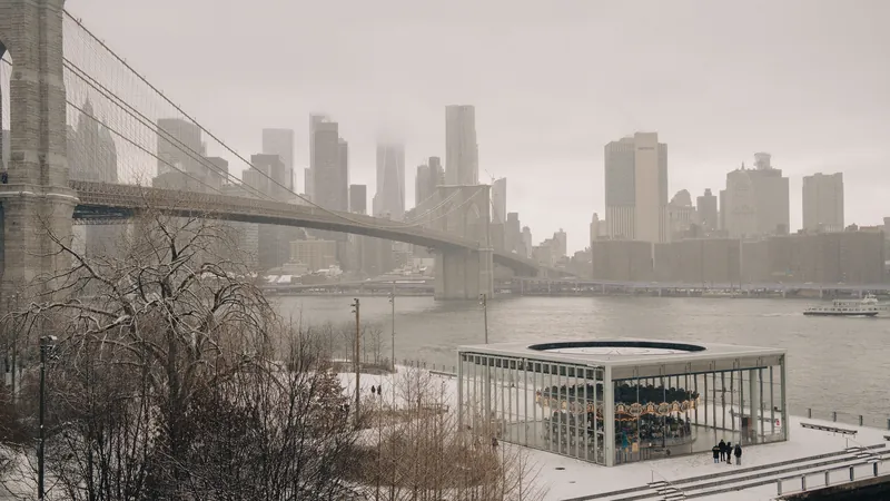 Winter view of Brooklyn Bridge and Manhattan skyline with snow-covered Jane's Carousel.