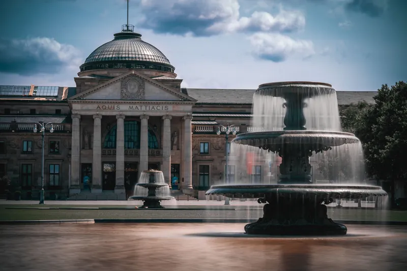 View of the neoclassical Kurhaus in Wiesbaden with a prominent foreground fountain.