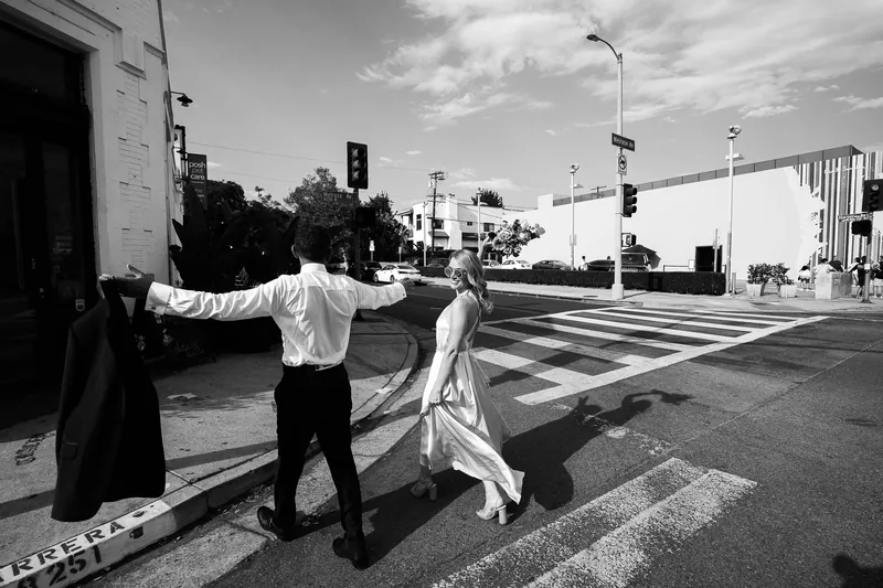 Stylish wedding couple crossing a Los Angeles street, captured in black and white.