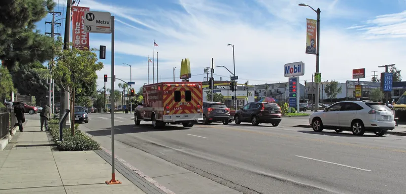 Looking east on Melrose Avenue toward its intersection with Vermont Avenue, Los Angeles. The ambulance will turn left on Vermont and head toward the three hospitals adjacent to Vermont and Sunset: Kaiser Permanente, Childrens Hospital LA, and Hollywood Presbyterian Medical Center. The banners for LACC are for LA City College, about 2 blocks north of this image on Vermont.