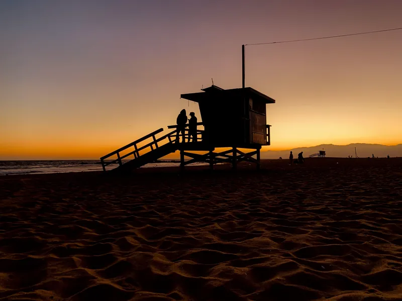 Silhouette of lifeguard station at sunset on Los Angeles beach. Perfect scene for tranquil evening vibes.