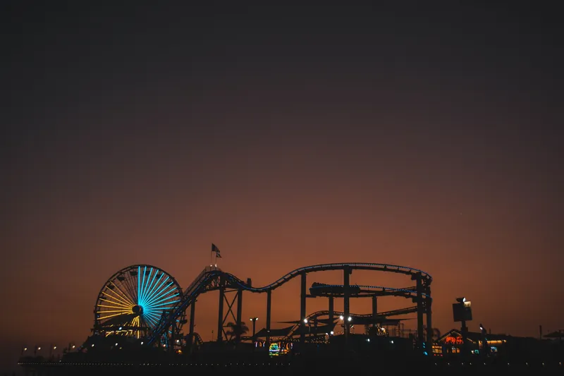 Silhouette of Santa Monica Pier with Ferris wheel glowing at dusk, capturing a vibrant evening scene.