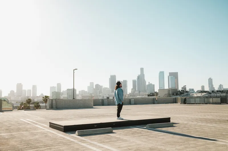 A lone individual on a rooftop with a stunning view of the Los Angeles skyline under clear skies.