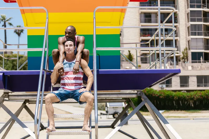 Happy interracial couple having fun at a colorful beach hut, symbolizing love and diversity.