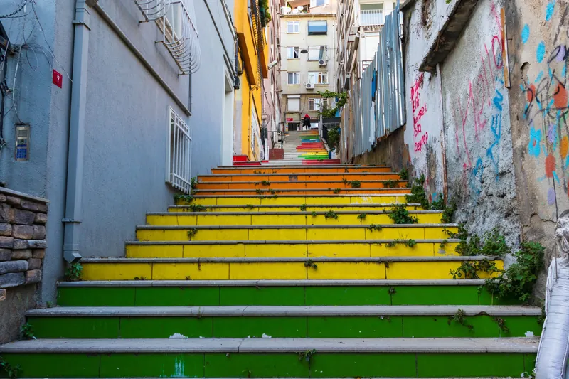 A vibrant urban staircase with colorful steps in a residential area, decorated with graffiti.