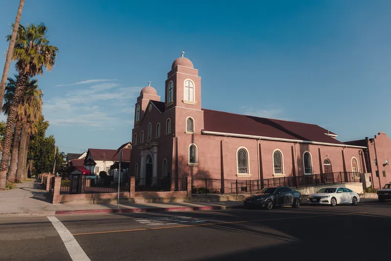 A picturesque urban church surrounded by palm trees on a bright, clear day.