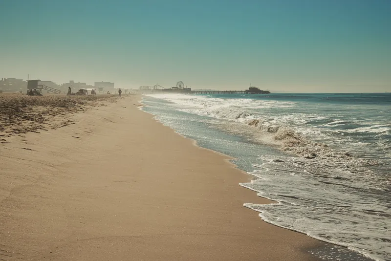 A serene view of Santa Monica Beach showcasing the iconic pier under a clear sky.