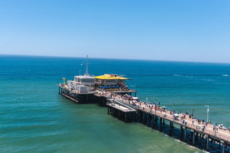 Scenic aerial view of Santa Monica Pier with vibrant blue ocean on a clear summer day.