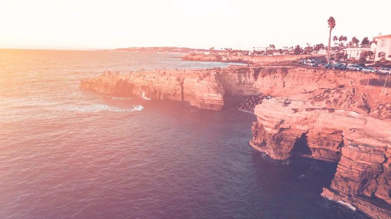 Stunning aerial capture of San Diego cliffs and ocean during a vibrant sunset, showcasing natural beauty.