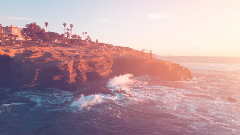 A breathtaking view of the sunset at La Jolla cliffs in San Diego with waves crashing against the rocks.