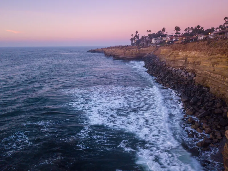 A breathtaking aerial view of Sunset Cliffs in San Diego at dusk, showcasing the rugged coastline and serene ocean waves.