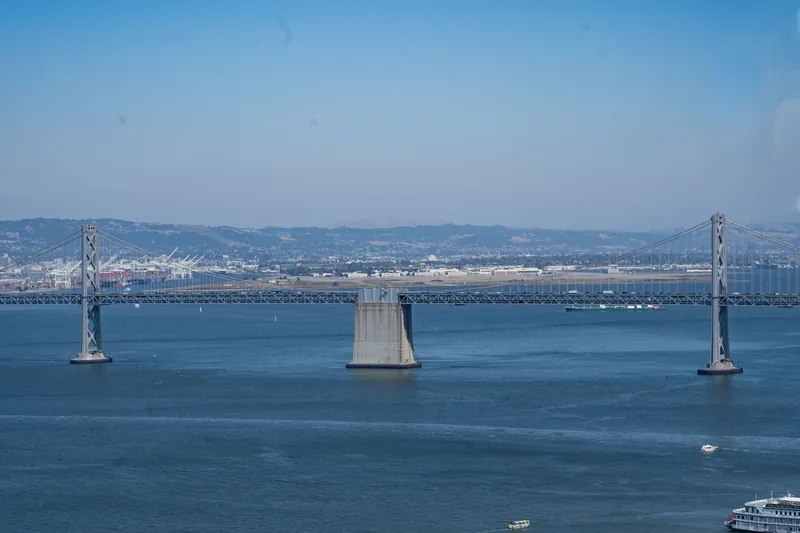 Scenic view of the Bay Bridge spanning across the San Francisco Bay under a clear blue sky.