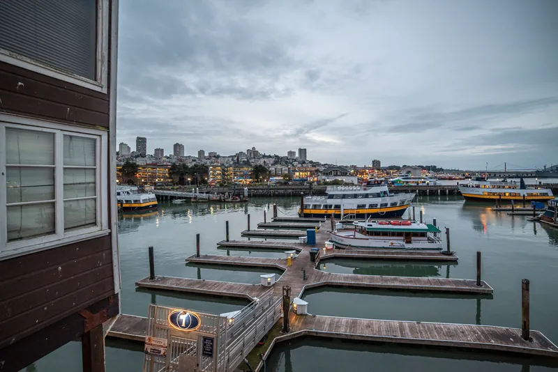 Capturing the serene waterfront of San Francisco with boats and skyline at dusk.