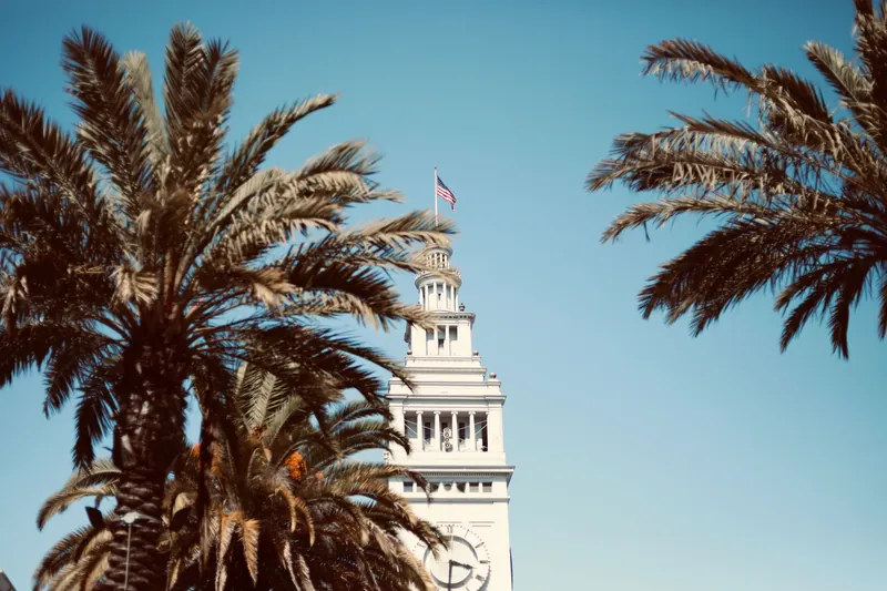The iconic San Francisco Ferry Building with palm trees and a clear blue sky.