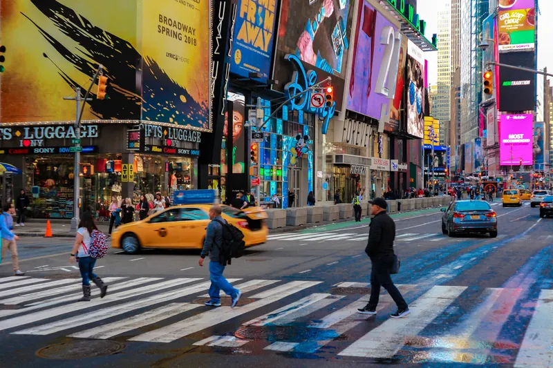 Times Square pedestrian crossing with billboards and taxis, capturing New York City's energy.