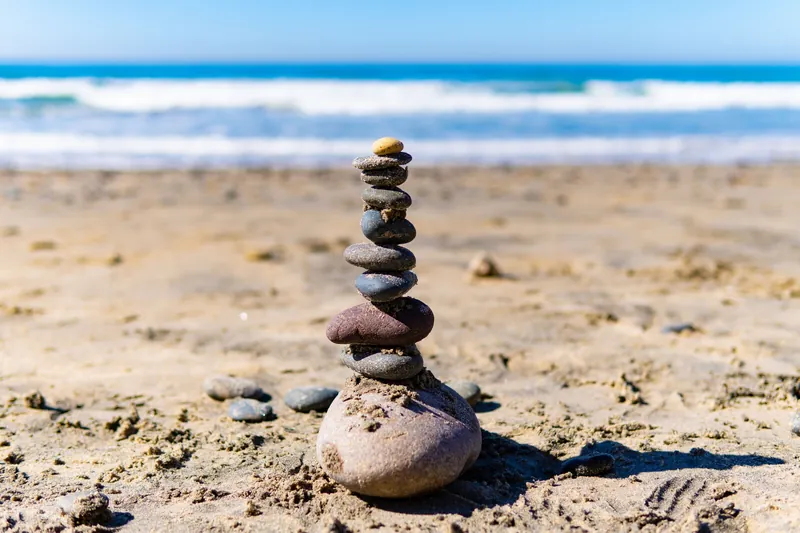 Calm stacked stones on a sunny San Diego beach, capturing balance and tranquility.