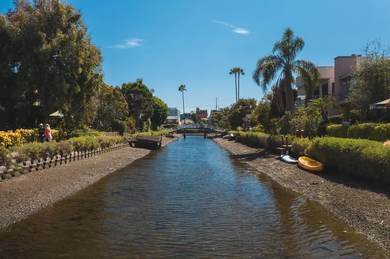 Beautiful view of Venice Canals in Los Angeles with lush greenery and clear blue sky.