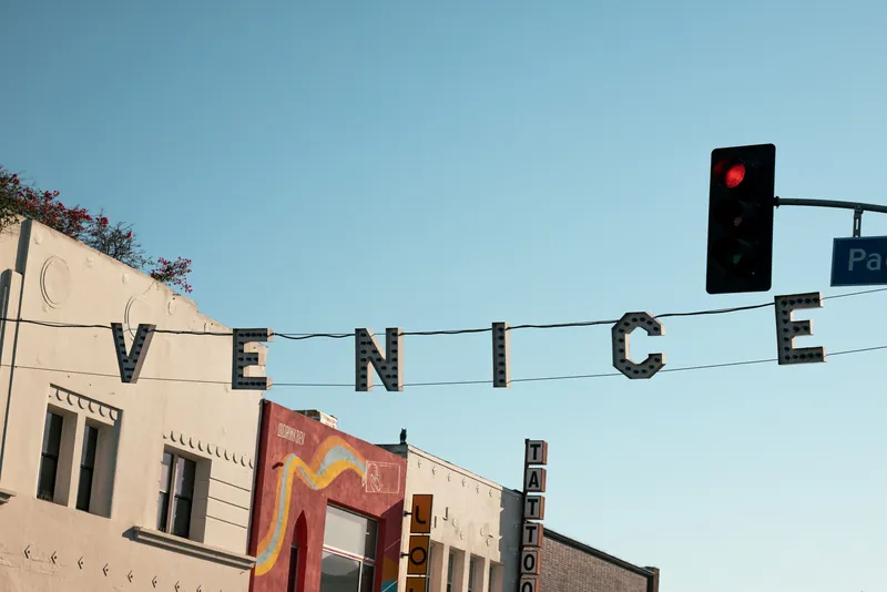 Venice Beach sign in Los Angeles under clear sky with traffic light and street view.
