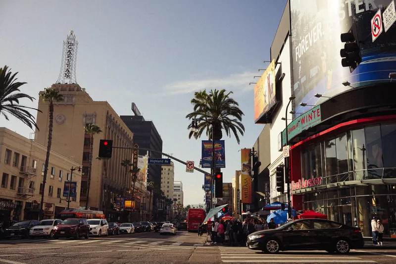A lively view of Hollywood Boulevard with iconic landmarks and busy street life under a clear sky.