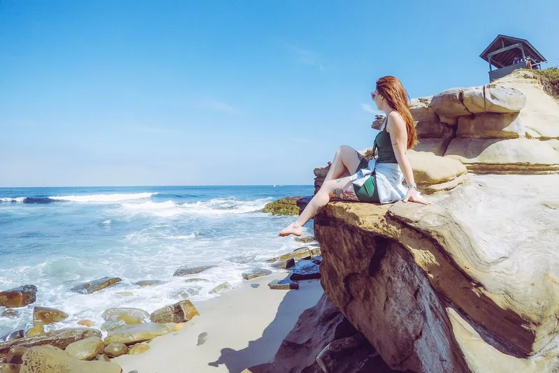 Woman enjoying a sunny day on the rocky beach of San Diego, California.